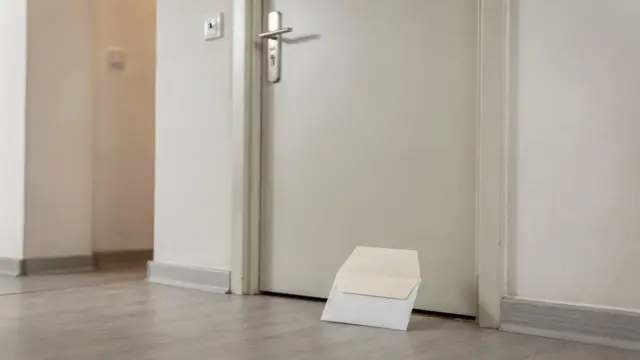 Briefumschlag vor einer Wohnungstür zum Thema Abmahnung im Mietrecht